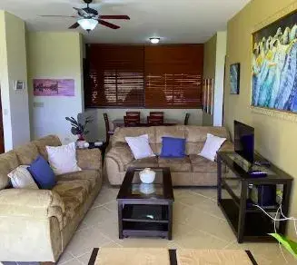 A Boquete Country Club living room, with a sectional sofa, television and timber blinds