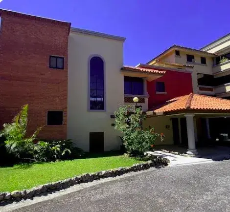A brick and cream house at Boquete Country Club, with an arched window and planted garden