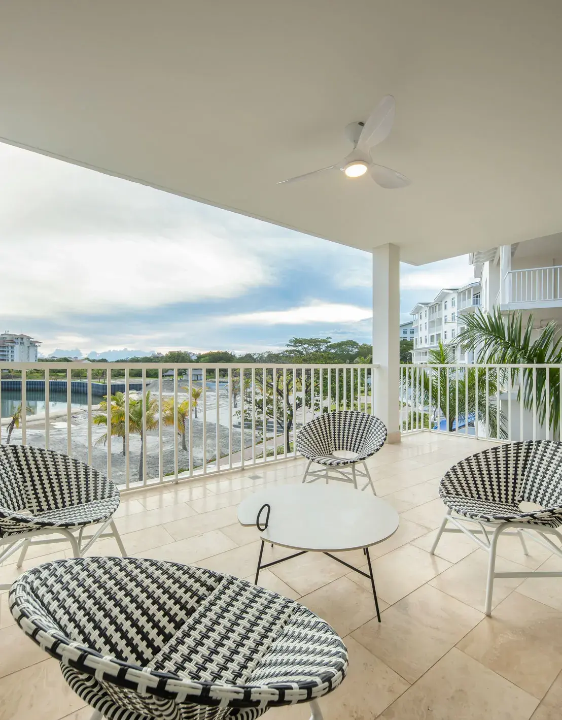 A furnished balcony at Buenaventura, with wire chairs and a table looking out over the resort and palms