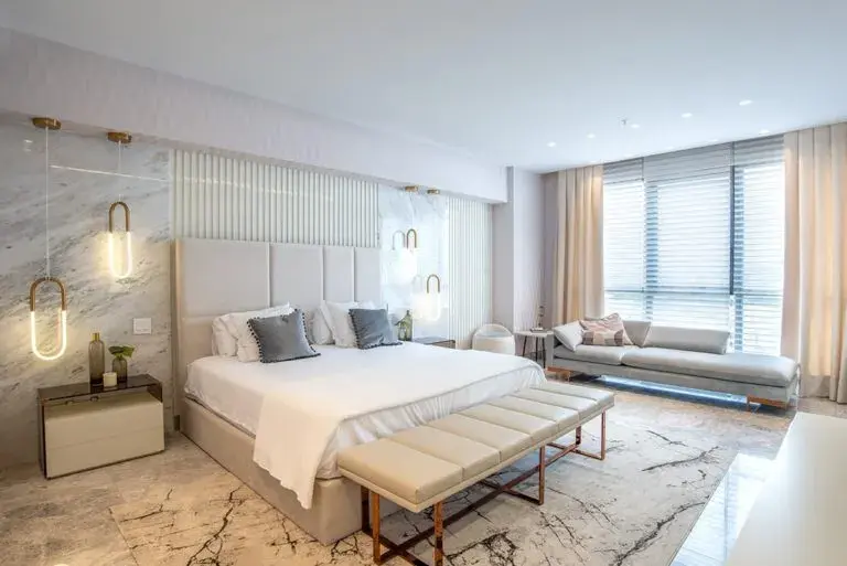 An Empire Residences bedroom, with a padded headboard, chaise and marble floor