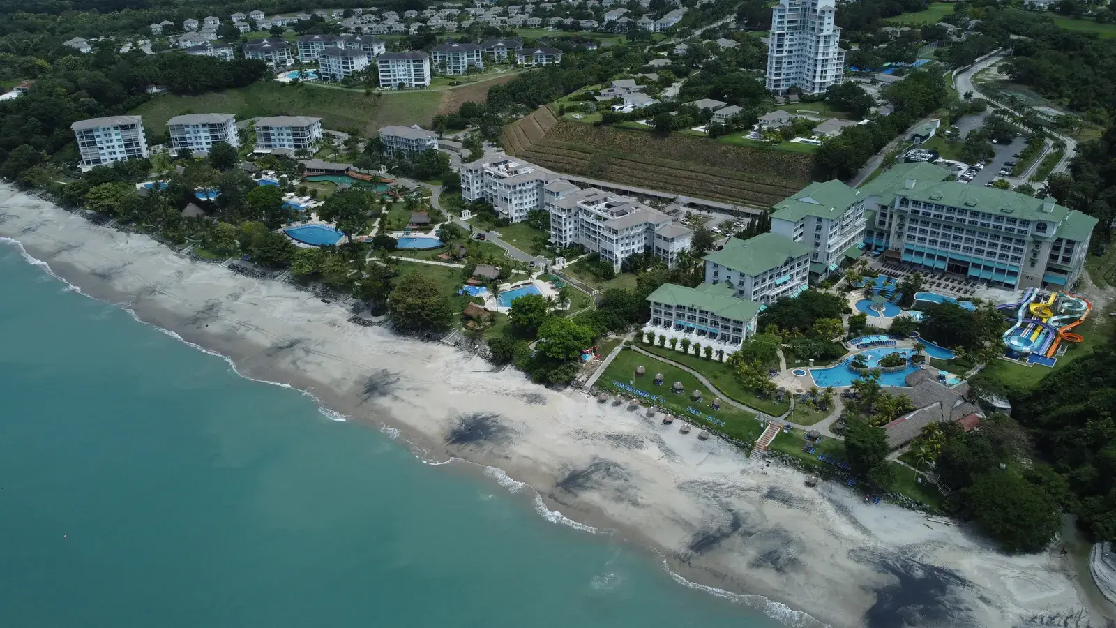 Aerial view of the Bijao resort, its low-rise buildings and pools set behind the Pacific beach