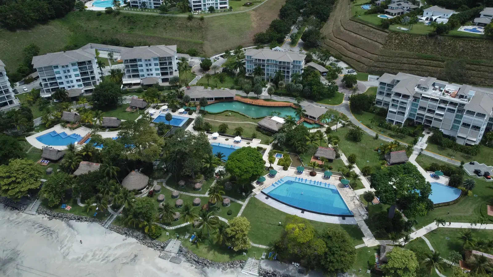 Aerial view over Bijao's pools and thatched pavilions, with the beach beyond