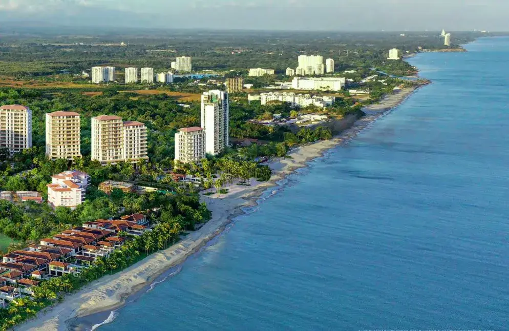 Aerial view of the Buenaventura coastline, with low-rise resort buildings set back from a curving Pacific beach