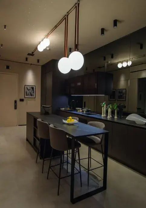 An Uptown kitchen, with a dark island, breakfast stools and pendant globes